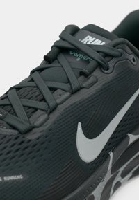 Detailný záber na čiernu bežeckú obuv Nike Vomero 18 s textúrovaným zvrškom, precízne uťahovanie šnúrok a bielym logom Nike swoosh na strednej podrážke.