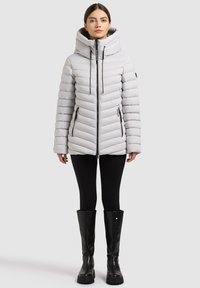 Světle šedá péřová bunda s vysokým límcem a kapucí, zdobená diagonálními prošitými liniemi, dvěma předními kapsami na zip a černými prvky.