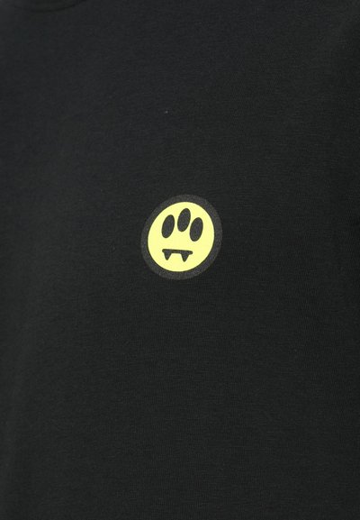 Svart bomull t-skjorte med et rundt gult grafisk merke som har tre prikker og tenner. Myk tekstur, enkelt design.