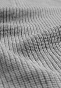 Sivkasti pleteni material z ribasto teksturo, ki vsebuje enakomerno razmaknjene navpične črte in mehak videz.