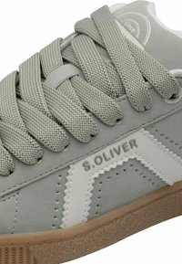 Hellgrauer Sneaker mit strukturiertem Obermaterial, glatten weißen Akzenten, rundem Logo und Gummisohle. Verfügt über dicke, gewebte Schnürsenkel und eine Detailnaht.