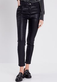Zwarte, glanzende skinny jeans met een fitted ontwerp, vijf zakken en een knoopsluiting. Het materiaal heeft een glanzende afwerking, wat zorgt voor een stijlvolle uitstraling.