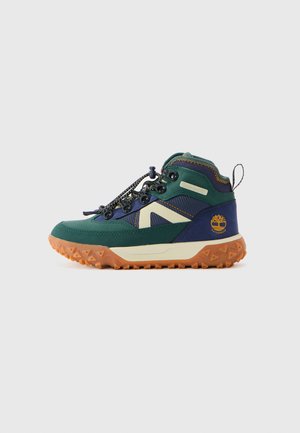 Grønn og marineblå vanntett fotturstsko med oransje såle, hvit mellomsåle, snøring og Timberland-logo på hælen.
