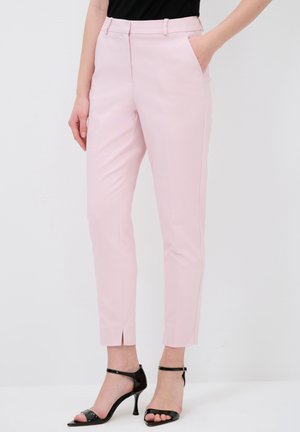 Lys pink tailored bukser med sidelommer, smal pasform og ankellængde, suppleret med sorte stiletter.