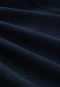 Marineblauwe stof met een zachte, gladde textuur, met sierlijke plooien en een uniforme uitstraling. Zijdeachtige afwerking voegt diepte toe.