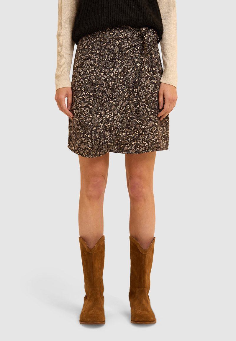Bruine bloemen wikkelrok van een textuurstof, met een strik in de taille. Gecombineerd met lichtbruine suede laarzen tot de knie.