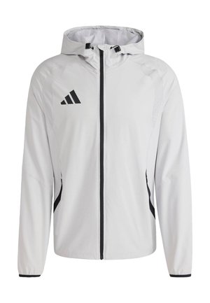 Giacca bianca leggera con cappuccio, dotata di cerniera e dettagli neri. Include un logo Adidas sulla parte superiore sinistra del petto.