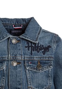 Jeansová bunda s klasickým střihem; světle modrá barva, kovové knoflíky a vyšívané logo "Hilfiger" na přední straně. Obsahuje náprsní kapsy.