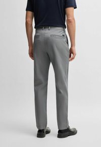Gray patterned trousers with a straight fit, flat front, two back pockets, and a waistband. Worn with black shoes.