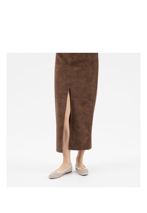 Untere Beine in einem braunen Midirock mit einem Schlitz vorne und weißen perforierten Ballettschuhen mit einer kleinen Schleifenverzierung.