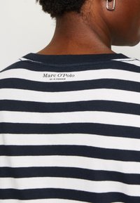 Marineblå og hvid stribet t-shirt med rund halsudskæring og korte ærmer. Har et lille mærke logo på den bageste halsområde. Lavet af bomuldsstof.