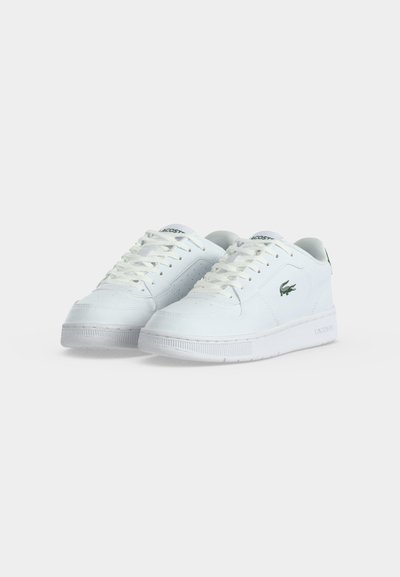 Двойка бели ниски маратонки Lacoste с връзки и зелен крокодилски лого отстрани, показани на обикновен фон.