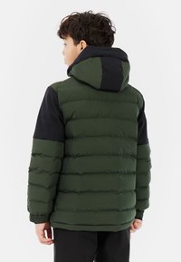 Groene en zwarte pufferjack met een capuchon, uitgerust met een gequiltde textuur, elastische manchetten en een ontspannen pasvorm. Eenvoudig ontwerp zonder zichtbare logo's.