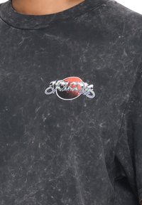 Czarna, krótki rękaw koszulka z zniszczon�ą teksturą, z okrągłym czerwono-srebrnym logo z napisem "Volcom" na klatce piersiowej.