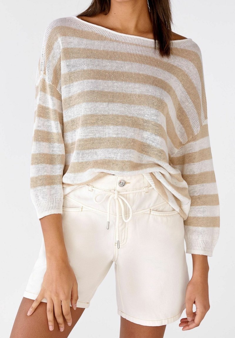 Beige en witte gestreepte gebreide trui met een brede halslijn en driekwartmouwen; gecombineerd met witte shorts met een tailleband met trekkoord.