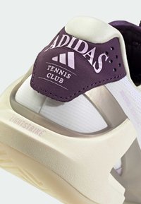 Baskets de tennis Adidas blanches et violettes avec un dessus lisse, un contrefort de talon de soutien et une semelle texturée avec le détail "LIGHTSTRIKE".