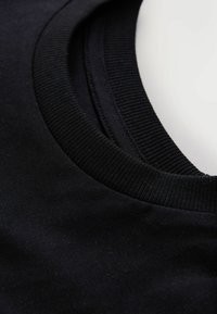 Fekete pamut póló bordázott kerek nyakkivágással és sima textúrával. Közeli kép a szövet és a varrás minőségének kiemelésére.