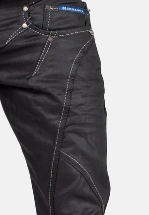 Jeans in denim nero con cuciture bianche a contrasto, cinque tasche e accessori in metallo. Il design presenta gambe affusolate e cuciture dettagliate.