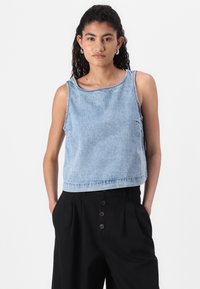 Jeansowy crop top w jasnoniebieskim kolorze z okrągłym dekoltem i bez rękawów, z surowymi krawędziami i subtelnymi detalami szycia. Połączony z czarnymi spodniami o wysokim stanie.