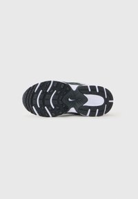 Semelle de chaussure de sport en noir et blanc avec du caoutchouc texturé pour une meilleure adhérence, présentant un motif circulaire et un détail de logo central.