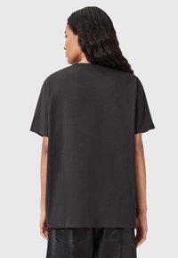 Musta puuvillainen t-paita, jossa on rento istuvuus, lyhyet hihat ja pyöreä pääntie. Tasainen tekstuuri, yksinkertainen muotoilu ilman näkyviä kuvioita tai korostuksia.