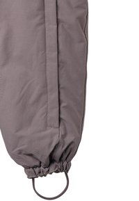 Szara pikowana odzież o zwężającym się kroju, z marszczonym mankietem i okrągłym uchwytem do ściągania, wykonana z gładkiej, lekkiej tkaniny.