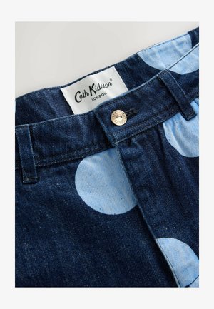 Mørk denimstof med store lyseblå prikker. Messingknaplukning med "Cath Kidston" mærket synligt nær taljen.