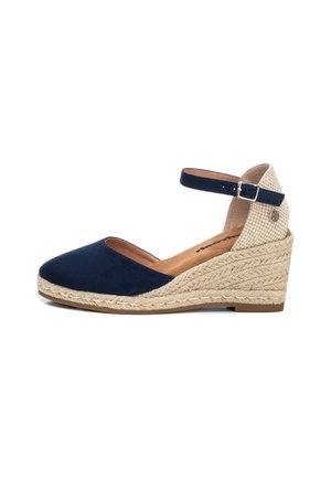Navy suede wedge heel shoe with a woven jute base, ankle strap, and tan insole featuring a checkered textile accent at the back.