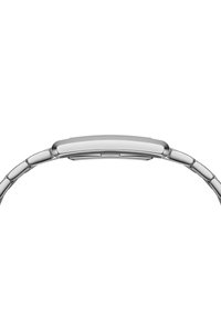 Montre en métal argenté au design épuré et plat avec une finition polie. Présente une surface lisse et des maillons entrelacés dans le bracelet.