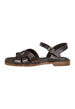 Sandalia plana para mujer con tiras cruzadas brillantes de color marrón oscuro, hebilla ajustable en el tobillo y suela de color marrón claro sobre fondo blanco.