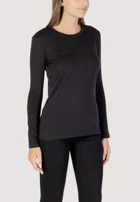 Schwarzes Langarm-T-Shirt aus weichem Stoff, mit Rundhalsausschnitt und dezentem Logo-Stick auf der Brust. Passt zu schwarzen Hosen.