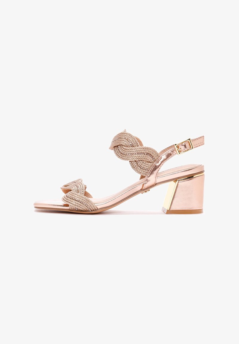 Beige Sandale mit gewobenem Riemen und Blockabsatz. Mit einem gewundenen Riemendesign und metallischen Akzenten am Absatz. Glatte Oberflächenstruktur.