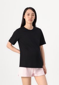 Black short-sleeve t-shirt with a round neckline, made from soft fabric, paired with light pink shorts featuring an elastic waistband.