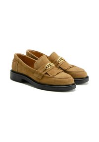 Mocassins en suède beige avec un dessus à franges et un détail en métal doré, dotés d'une semelle en caoutchouc noire et d'une forme plate classique.