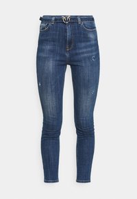 Vaqueros de denim azul ajustados con ligero desgaste, herrajes plateados y un lazo decorativo en la parte superior.