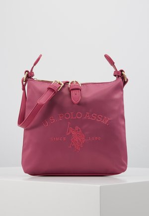 Bolso bandolera rosa con correa ajustable, detalle de hebilla y logotipo bordado en rojo de U.S. Polo Assn. con un jugador de polo a caballo.