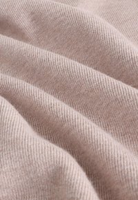 Rosa ribbad tyg med en mjuk textur, som har subtila räfflor skapade av stickmönstret och faller mjukt i veck.