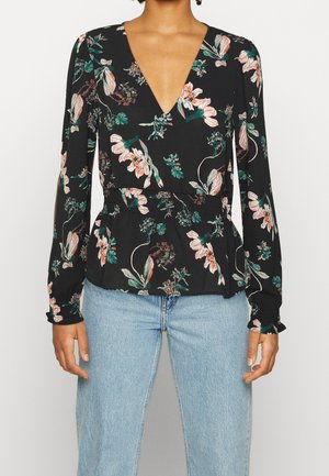 Czarna kwiatowa bluzka z długim rękawem z różowymi i zielonymi kwiatami, dekolt w serek, taliowana, noszona z jasnoniebieskimi, wysokim stanem jeansami.