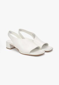 Białe skórzane buty slingback z otwartym noskiem, niskim blokowym obcasem i gładkim wykończeniem. Akcenty to boczne wycięcia.