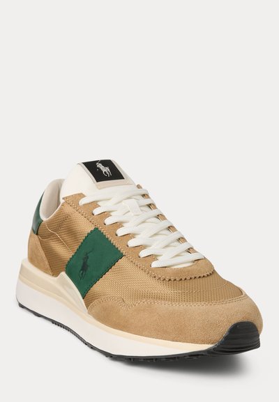 Vīriešu sneakers tan krāsā ar zamšādu un tīkla elementiem. Iezīmē zaļu akcentu paneli, baltas auklas un melnu logotipu uz mēles. Noapaļota purngala un mīksts zolīte.