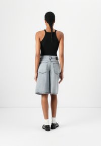 Svart ärmlös bodysuit kombinerad med ljusgrå denimshorts med fickor och rak skärning, bärs med svarta skor och vita strumpor.
