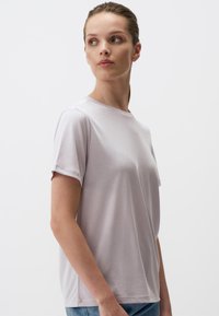 T-shirt grigio chiaro a maniche corte realizzato in tessuto morbido, con colletto rotondo classico e vestibilità rilassata, caratterizzato da un dettaglio discreto sulle spalle.