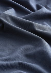 Teksturoitu tumman sininen kangas, jossa on hienovarainen kudonta, esittää taitteita ja pehmeää laskostusta. Materiaali vaikuttaa sileältä ja siinä on kevyt kiilto.