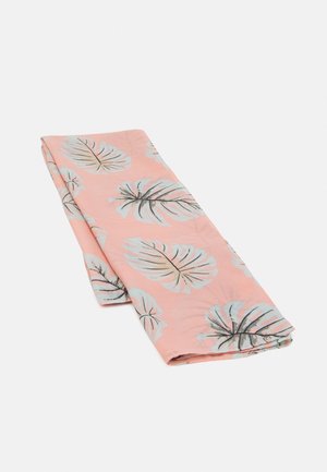 Folded pink fabric with a pattern of large white and gray tropical leaves, displayed on a plain light background.