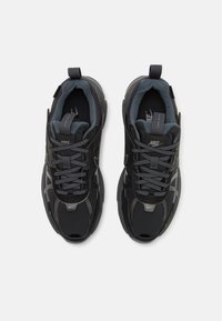 Paire de baskets Nike noires et grises avec lacets, col rembourré et étiquettes de languette de marque, vues de dessus sur fond blanc.