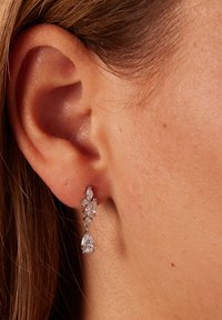 Ohrringe mit Anhänger in Silberfassung, versehen mit klaren Tropfen- und Marquise-Schliffsteinen, zarten Kettengliedern und einer polierten Oberfläche.