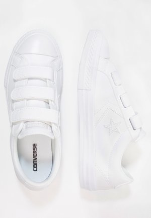 Paire de baskets blanches Converse avec des bandes velcro, logo étoile sur le côté et semelles en caoutchouc, vues de dessus et de côté.