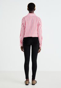 Chemise rayée rouge et blanche, leggings noirs et ballerines à imprimé animal. Elle présente des manches longues, un col et une coupe ajustée.