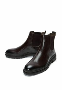 Stivali Chelsea in pelle marrone scuro con finitura testurizzata, pannelli laterali elasticizzati e suola in gomma nera. Presentano linguette per un facile indossamento.