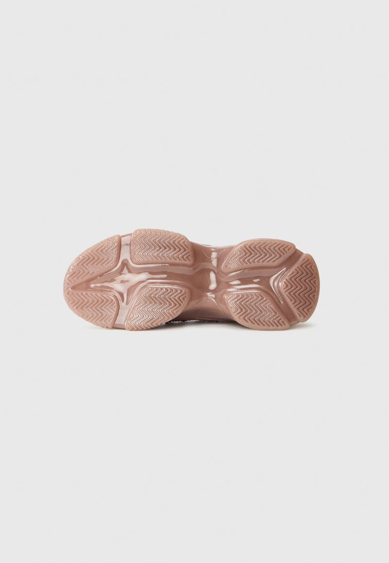 Semelle d'une chaussure de sport rose, avec un motif de grip texturé et un design sculpté, placée sur un fond blanc.